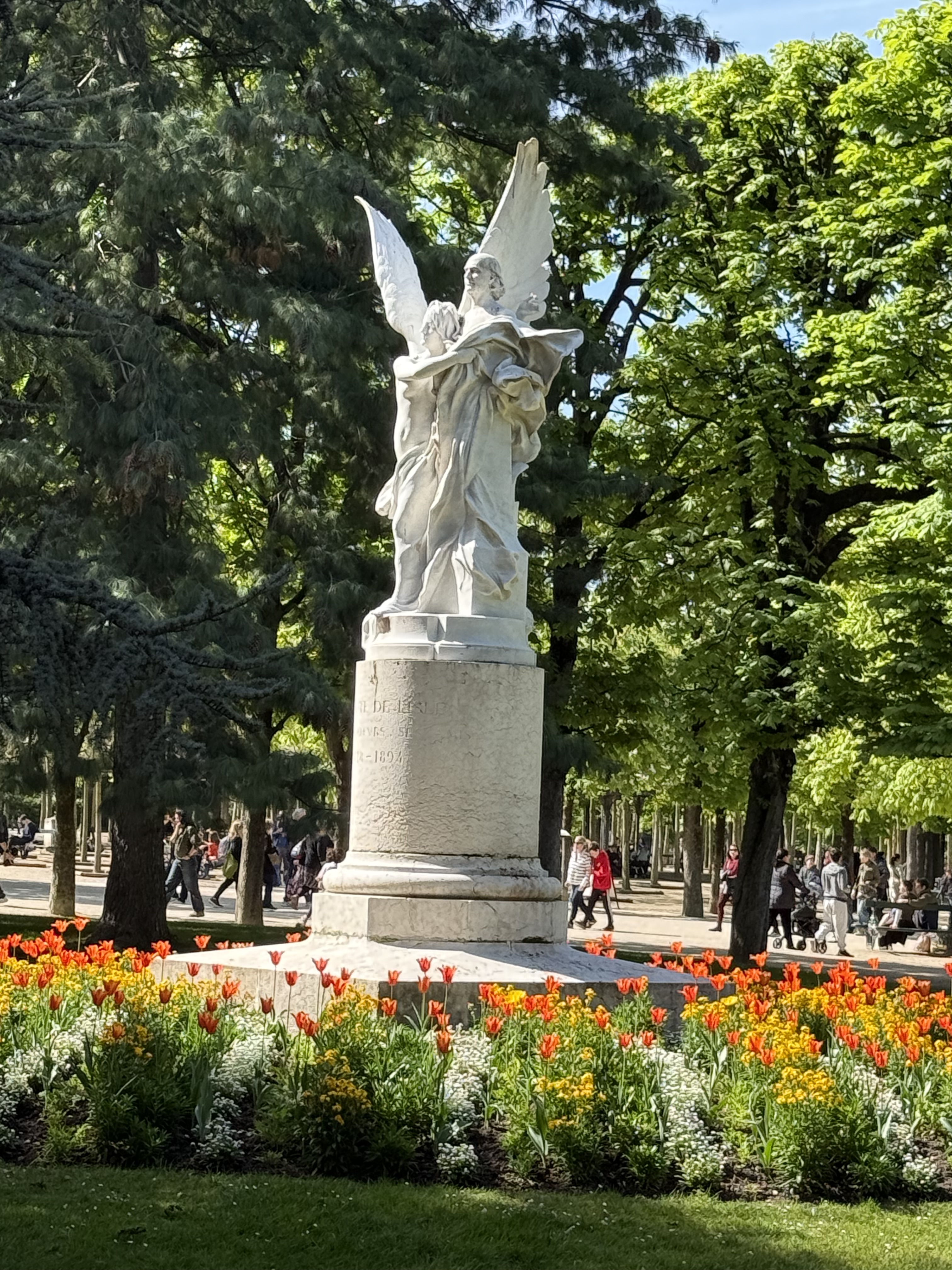 White Monument to Leconte de Lisle in a flowerbed of orange and yellow tulips
