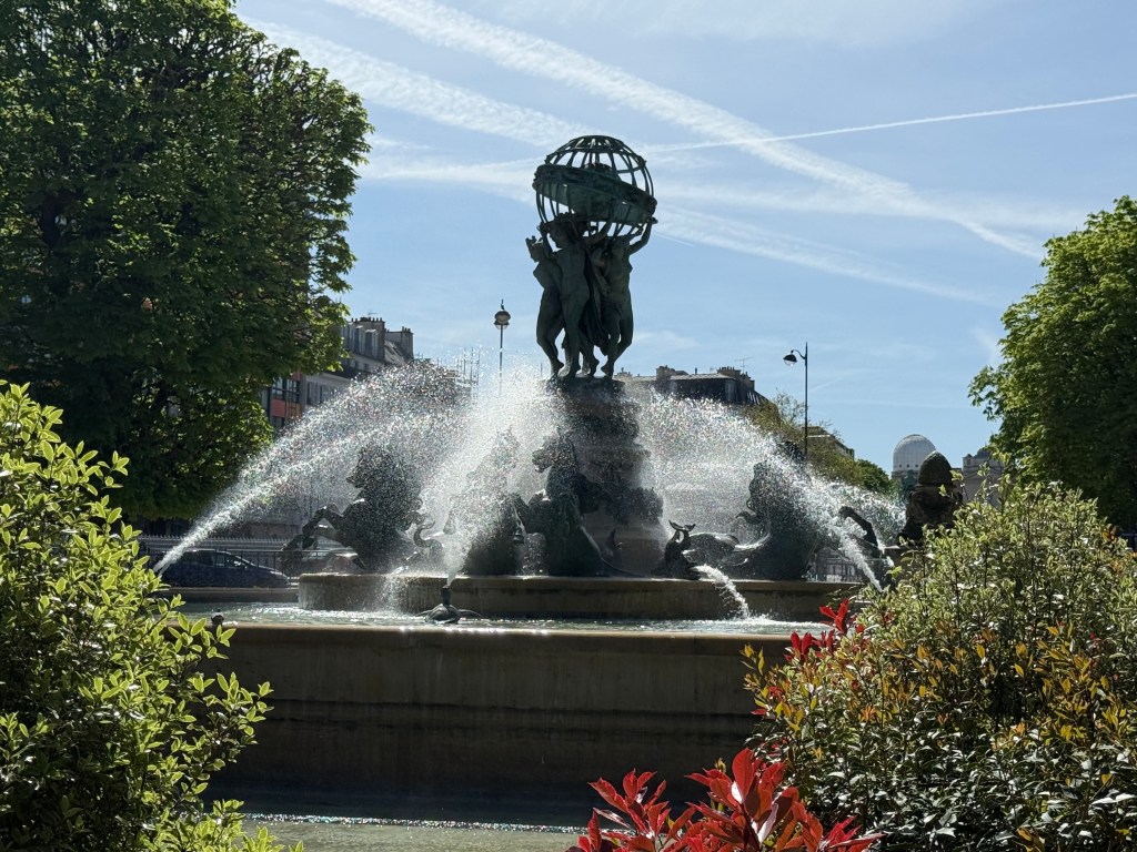 Frontal view of the fountain into the sun. The water sparkles but the statue is a silhouette