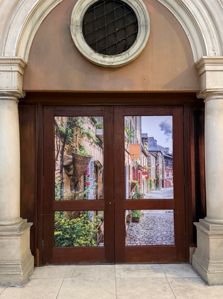 Close up of doors painted with an Italian summer street scene featuring lots of greenery.